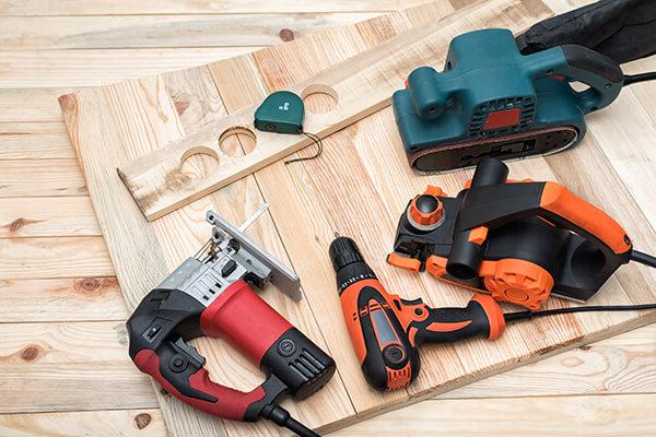 Set of handheld woodworking power tools for woodworking and workpiece lies on a light wooden background